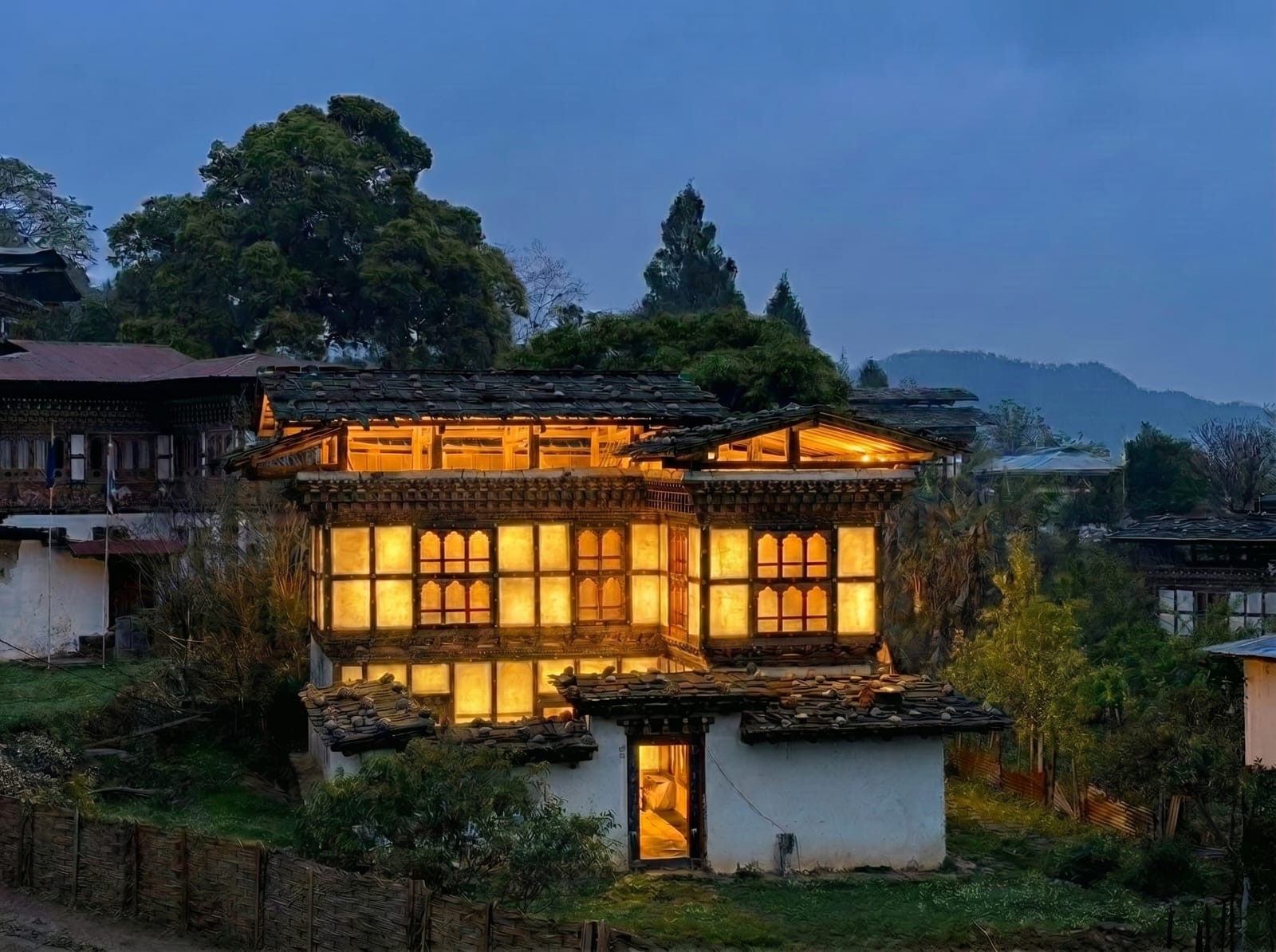 Illuminated traditional Bhutanese house at dusk, photographed in Bhutan